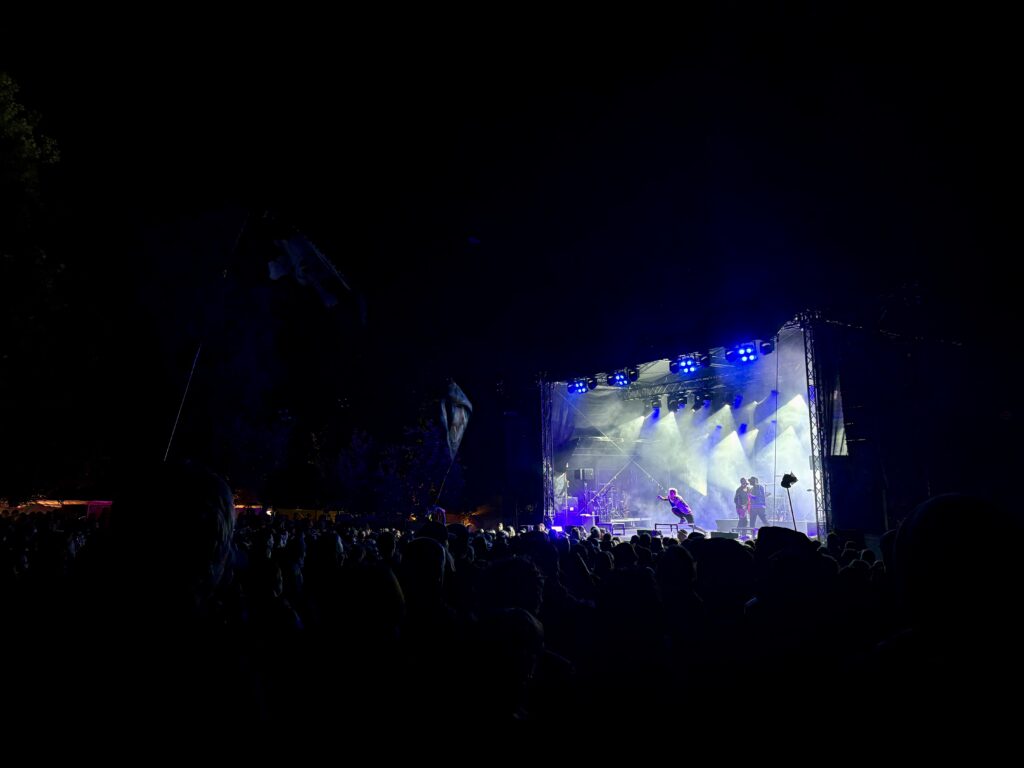 Weit entfernte, blau beleuchtete Bühne auf dem dunklen Festivalgelände.